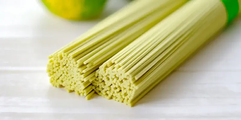 すだちの実を背景に、束ねて置かれた乾麺のすだち麺